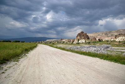 Road passing through landscape against cloudy sky