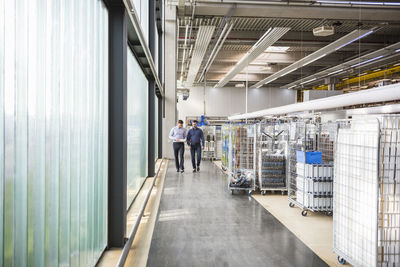 Two men walking in factory shop floor talking about product