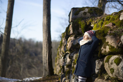 Side view of woman leaning on rocks