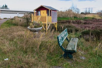 Abandoned chair on field against sky