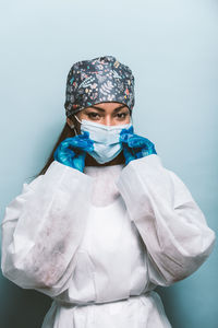 Portrait of doctor wearing mask against blue background