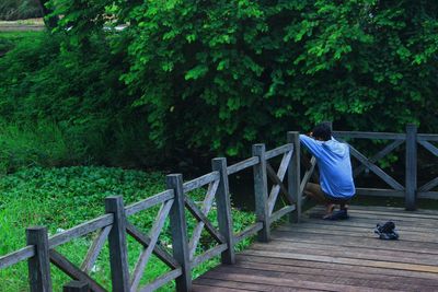 Rear view of woman walking on footbridge in forest