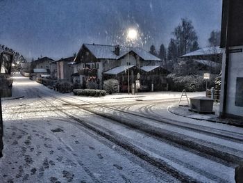 Snow covered houses against sky at night