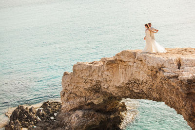 Woman standing on rock by sea