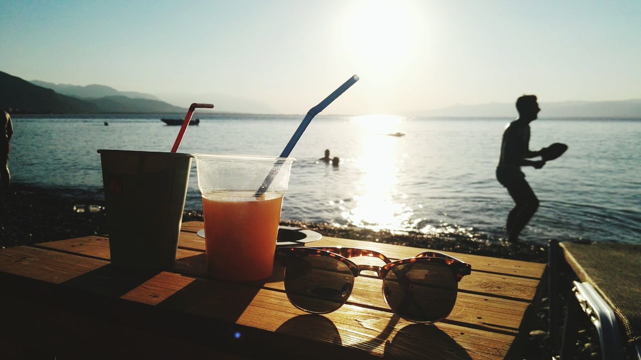 drink, sunlight, sea, water, sunset, sun, refreshment, silhouette, food and drink, drinking glass, nature, outdoors, table, summer, vacations, day, mountain, beach, beauty in nature, scenics, sky, freshness, horizon over water, no people