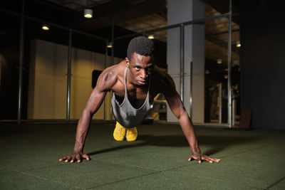 Athletic man doing push-ups exercise at gym