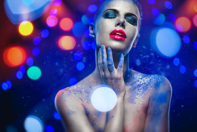 Seductive naked woman with glitter against blue background