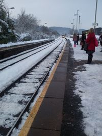 People at railroad station against sky