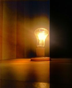 Illuminated light bulb on table at home
