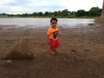 Boy standing in water against sky