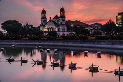 Reflection of building on lake against sky during sunset