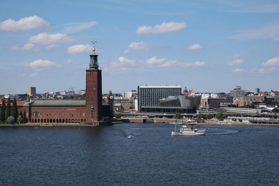 Buildings at waterfront against cloudy sky