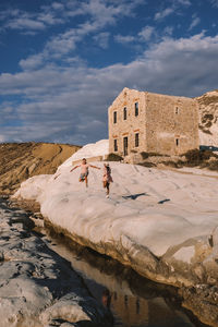 People walking on rocks against the sky