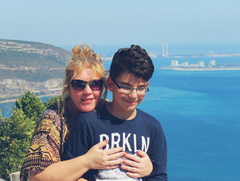 Happy mother embracing son against sea