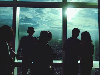 Silhouette men on window against sky