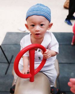 Portrait of cute boy holding red umbrella