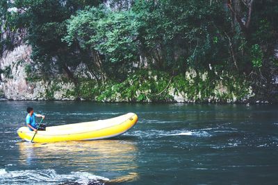 Man oaring inflatable raft in river