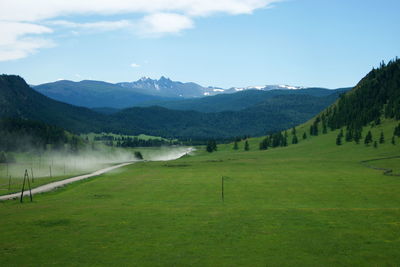 Scenic view of green landscape and mountains against sky