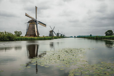 Lined windmills aside canal in a cloudy day at kinderdijk. a polder the country of netherlands.