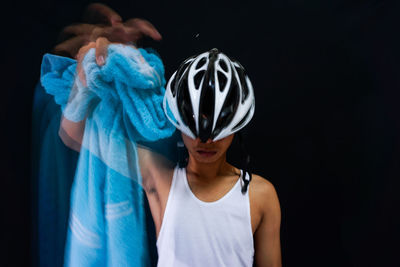 Multiple exposure image of man holding towel and wearing cycling helmet against black background