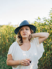Young millennial woman outdoors at apple orchard enjoying glass of wine in  golden hour sunset