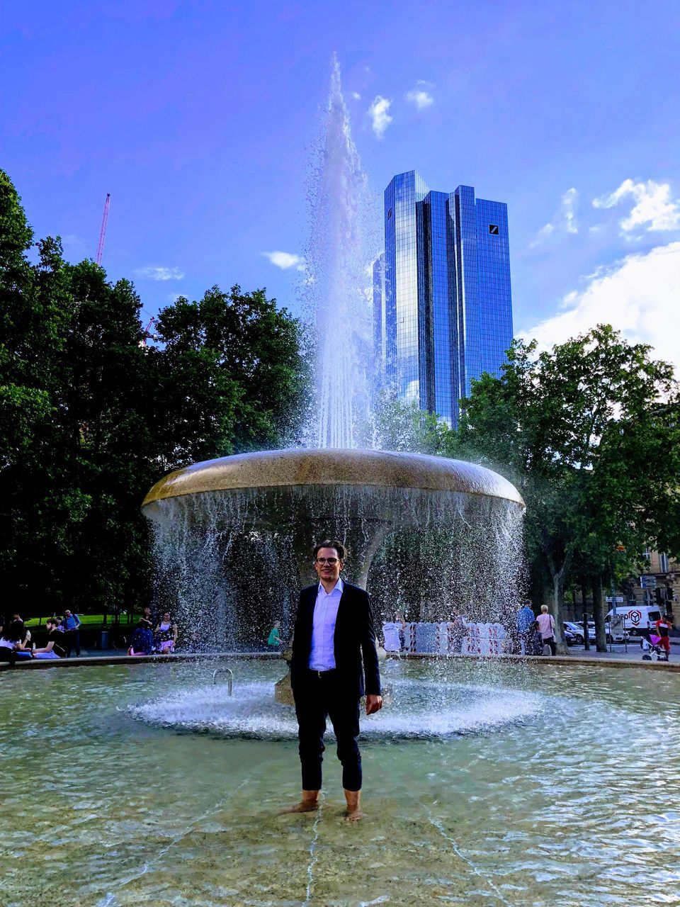 water, architecture, fountain, motion, one person, real people, tree, nature, spraying, standing, built structure, lifestyles, city, splashing, building exterior, long exposure, sky, waterfront, outdoors, flowing water, flowing