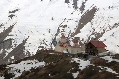 Snow covered houses by buildings against mountains