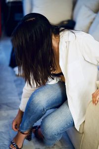 Side view of woman sitting on bed at home