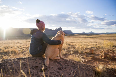 A woman and her yellow lab enjoying a beautiful desert sunset.