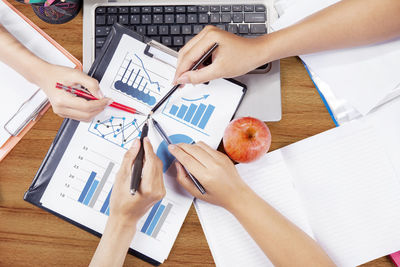 Cropped hands of colleagues working over graph in office