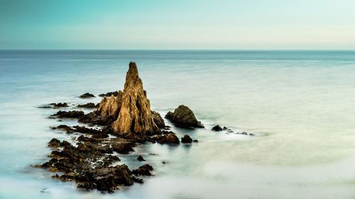 Rock formation on beach against sky