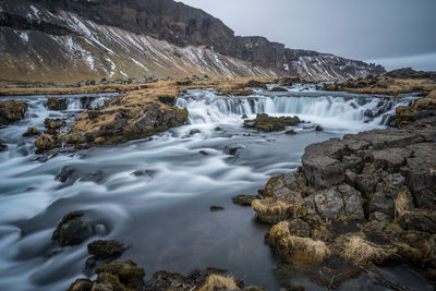 Scenic view of waterfall against sky