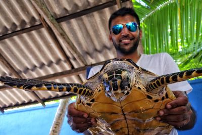 Low angle portrait of young man holding turtle