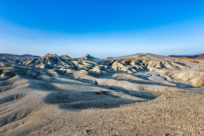 Scenic view of arid landscape against blue sky