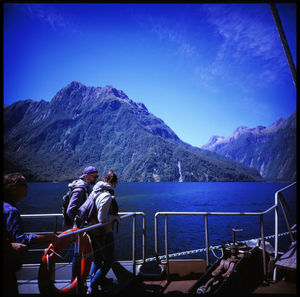 People looking at mountains against blue sky