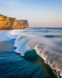 Drone photograph of large waves crashing off the coast of uluwatu in bali, indonesia