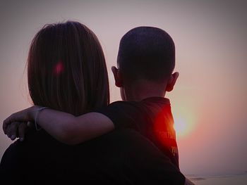 Rear view of couple kissing against sky