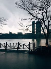 Bridge over river by buildings in city against sky