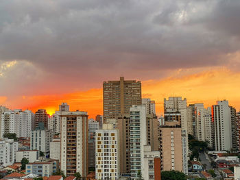 Modern buildings in city against sky during sunset