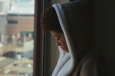 Close-up of woman looking through window at home