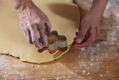 Cropped hands of chef cutting dough with pastry cutter at table