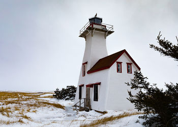 Low angle view of lighthouse on snow covered field against sky