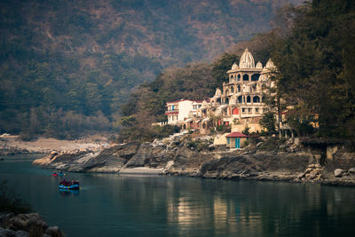 Scenic view of lake by buildings against mountain