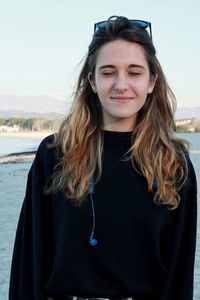 Portrait of smiling young woman standing against water