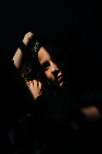 Portrait of young woman against black background
