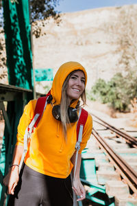 Smiling young woman standing by railroad track