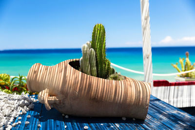 Close-up of deck chairs on beach against blue sky