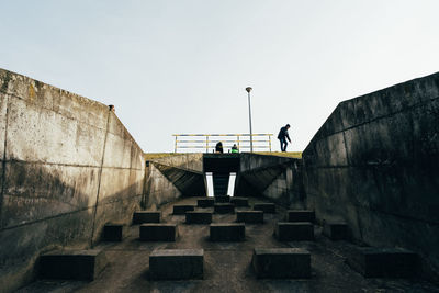 Low angle view of men standing on staircase against clear sky