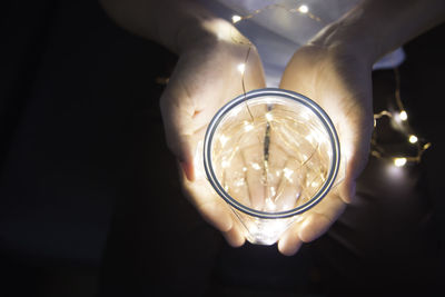 Close-up of hand holding illuminated light bulb