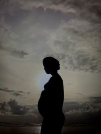 Silhouette woman standing against sky during sunset